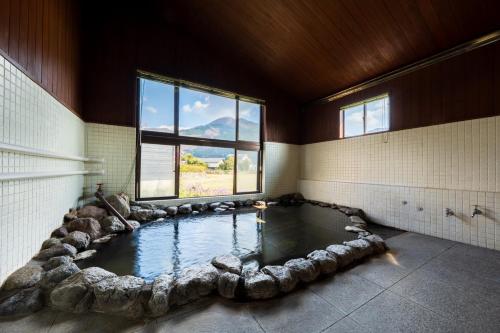 a bathroom with a pool of water with rocks around it at ホテル 木綿恋記 -Hotel Yufugoiki- in Yufu