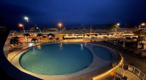 a large swimming pool at night with a beach at Suíte Luxo Mar em Hotel Nacional in Rio de Janeiro