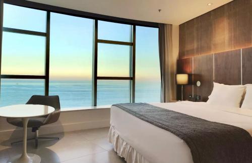 a bedroom with a bed and a table and windows at Suíte Luxo Mar em Hotel Nacional in Rio de Janeiro