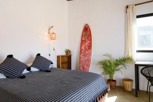 a bedroom with a bed and a surfboard on the wall at Ohana cerritos in El Pescadero