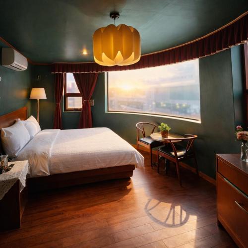 a bedroom with a bed and a table and a window at Gangneung Wheel Hotel in Gangneung