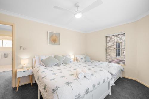 a white bedroom with a large bed and a window at Ocean Shores Apartment 2 in South West Rocks