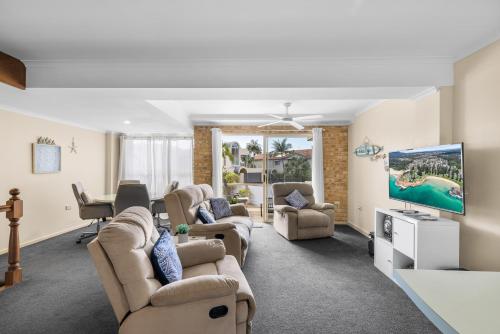 a living room with couches and a flat screen tv at Ocean Shores Apartment 2 in South West Rocks