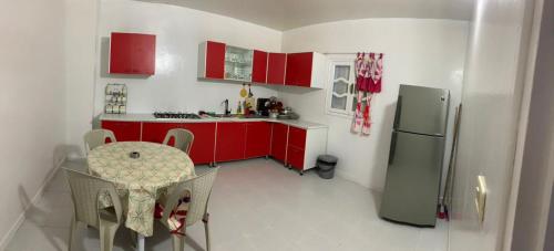 a kitchen with red cabinets and a table and a refrigerator at Maison yassine in Douz