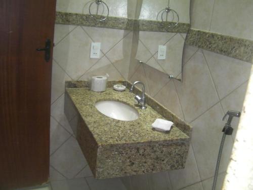 a bathroom sink with a granite counter top at Pousada Dom Diego in Jacaraípe