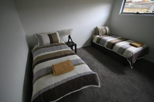 two twin beds in a room with a window at Cedar Cottages Blackmans Bay in Kingston