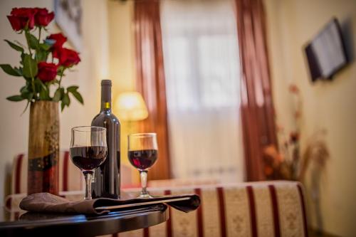 a table with two glasses of wine and a vase with roses at Hotel Rina Cerbul in Sinaia