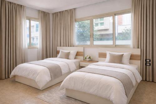 two beds in a bedroom with two windows at Villa Celia -New Cairo in Cairo