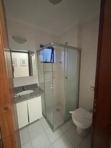 a bathroom with a glass shower and a toilet at Flats Beira Mar in Caraguatatuba