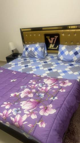 a bed with a purple bedspread with flowers on it at Zac Mbao appartement en face de la place in Mbaw