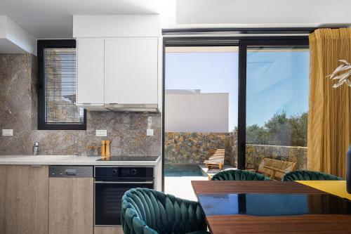 a kitchen with white cabinets and a table and chairs at Seafront Luxury Moonlight Villa in South East Crete with Breathtaking Views in Makry Gialos
