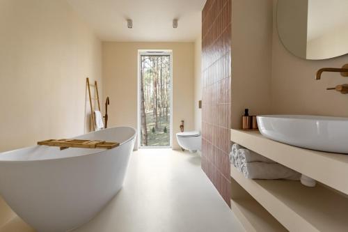a bathroom with a large white tub and a sink at Forest Hub Popowo in Huta Podgórna