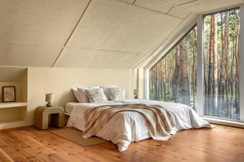 a bedroom with a bed and a large window at Forest Hub Popowo in Huta Podgórna