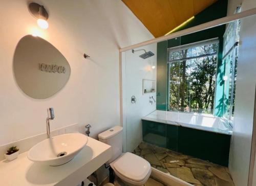 a bathroom with a sink and a toilet and a window at Chalé da árvore Buzios in Búzios