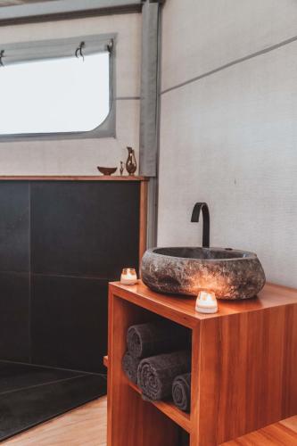 a bathroom with a stone sink on a wooden stand at Te Awa Glamping in Taumarunui