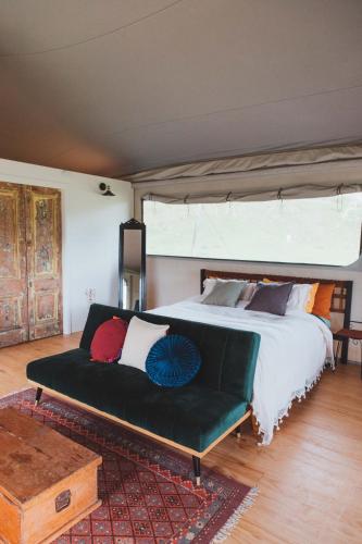 a bedroom with a large bed with a green couch at Te Awa Glamping in Taumarunui
