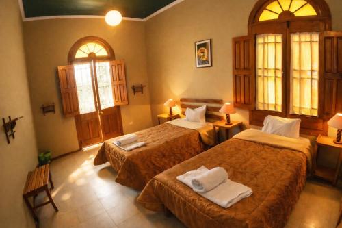 a hotel room with two beds and two windows at El Caminante Class in Arequipa