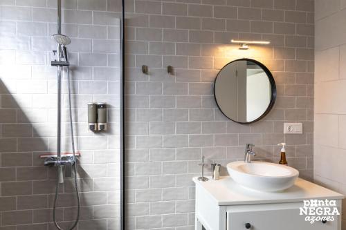 a bathroom with a shower with a sink and a mirror at Beer House by PontaNegraAzores in Altares