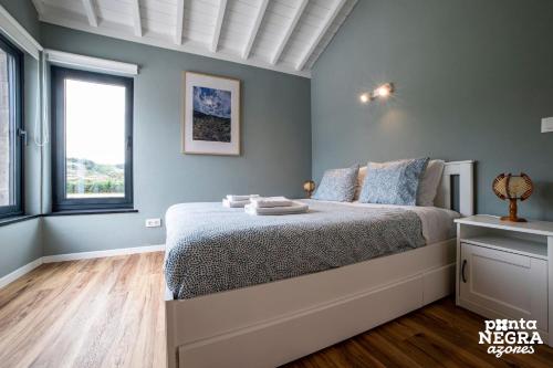 a bedroom with a bed with blue walls and a window at Beer House by PontaNegraAzores in Altares