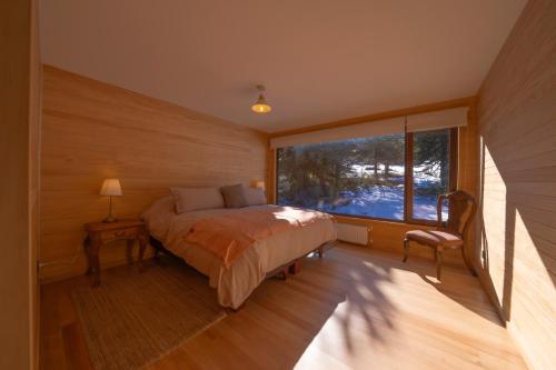 a bedroom with a bed and a large window at Cuyul Lodge in Malalcahuello