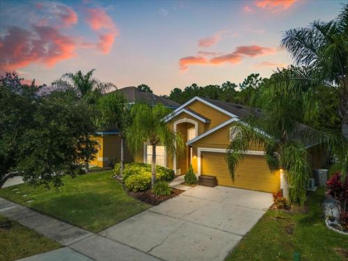 a house with a yellow garage in a yard at 5 Bedrooms 3 Bathrooms Veranda Palms 4458 NP in Orlando