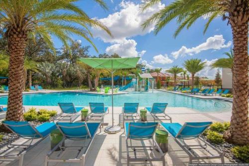 a pool at the resort with blue chairs and palm trees at 5 Bedrooms 3 Bathrooms Veranda Palms 4458 NP in Orlando