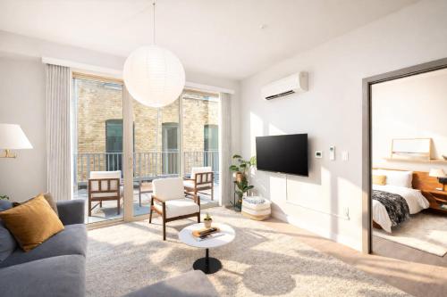 a living room with a couch and a bed and a television at Charming Walker's Point Apt with Balcony | Sleeps 4 in Milwaukee