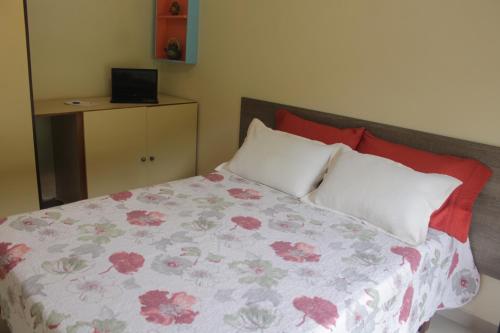 a bedroom with a bed with red and white pillows at Pousada Porto Paraiso, o seu Paraíso Escondido no Guarujá in Guarujá
