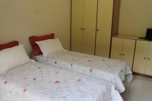a bedroom with two beds with pink flowers on them at Pousada Porto Paraiso, o seu Paraíso Escondido no Guarujá in Guarujá
