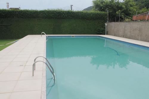 a swimming pool with blue water in a yard at Pousada Porto Paraiso, o seu Paraíso Escondido no Guarujá in Guarujá