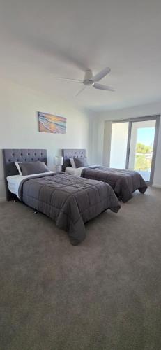 two beds in a bedroom with a ceiling fan at Coastal Calm Seascapes unit 3 in Falcon