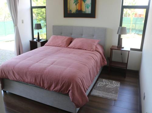 a bedroom with a bed with a pink comforter at Villa Nomad in Naranjito