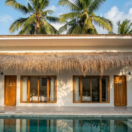 a resort with a swimming pool and palm trees at CASA Habibi in Kuta Lombok