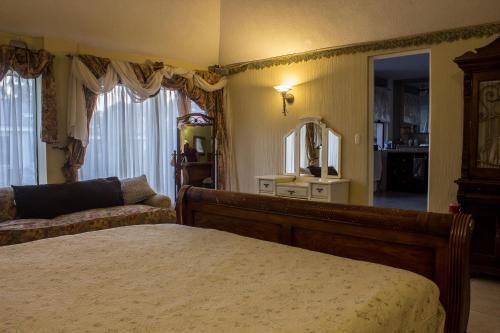a bedroom with a bed and a couch and a mirror at Mi casa, tu casa in Guatemala