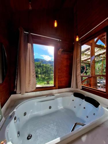 a bath tub in a room with a window at Chalés Refúgio no Campo in Santo Antônio do Pinhal