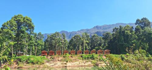 a row of houses on a hill in front of a mountain at Konglor cave Resort - River side Restaurant in Ban Konglo