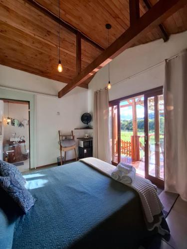 a bedroom with a large bed with a blue blanket at Chalés Refúgio no Campo in Santo Antônio do Pinhal