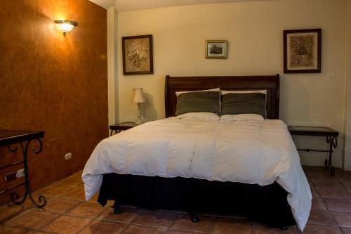 a bedroom with a bed with white sheets and pillows at Mi casa, tu casa in Guatemala