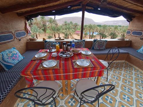 a table and chairs on a patio with palm trees at Maggaman Guest House in Tafraoute Sidi Ali
