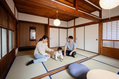 a family sitting on the floor of a room with a baby at Kizuna House Yuzuriha in Minamiawaji
