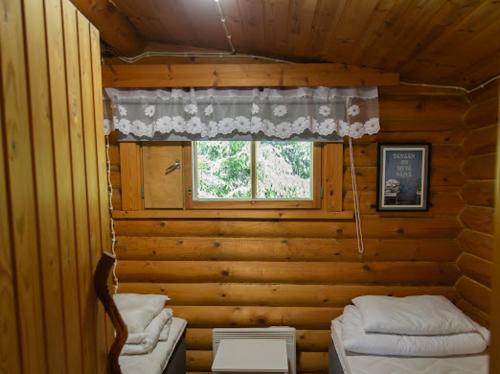 a room with two beds and a window in a log cabin at Juhantupa in Keuruu
