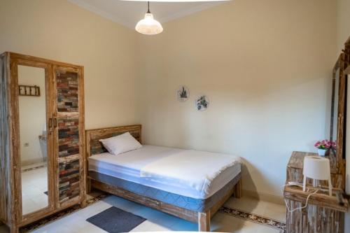 a bedroom with a bed and a mirror at Sabi House Lesmana in Timuran
