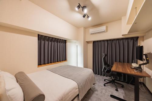 a bedroom with a bed and a desk with a computer at Work Friendly Room 3 min to Station Simmons Bed WiFi and Desk in Nagoya