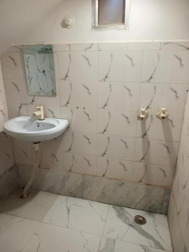 a white tiled bathroom with a sink and a mirror at Vrindavan Bunk Hostel by Shiva - 5min Walk from Prem Mandir in Vrindāvan