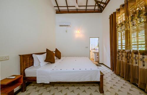 a bedroom with a white bed and a window at Ahungalla Ocean Villa in Ahungalla