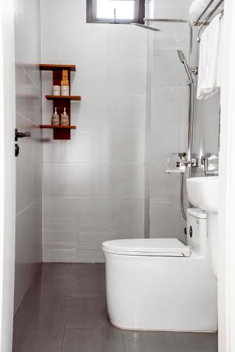 a white bathroom with a toilet and a sink at Cát Boutique Hotel in Dong Hoi
