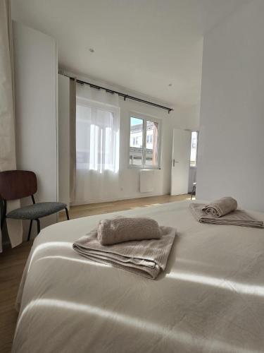 a white bedroom with two towels on a bed at La Tour d'Harfleur 1 in Caudebec-en-Caux
