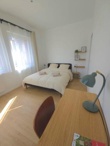 a bedroom with a bed and a desk with a lamp at La Tour d'Harfleur 2 in Caudebec-en-Caux