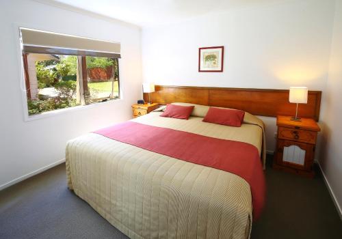 a bedroom with a large bed and a window at Poinciana Cottages in Burnt Pine