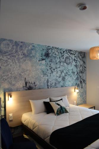 a bedroom with a large white bed with a painting on the wall at Brit Hotel Au Pays De Vitré in Étrelles
